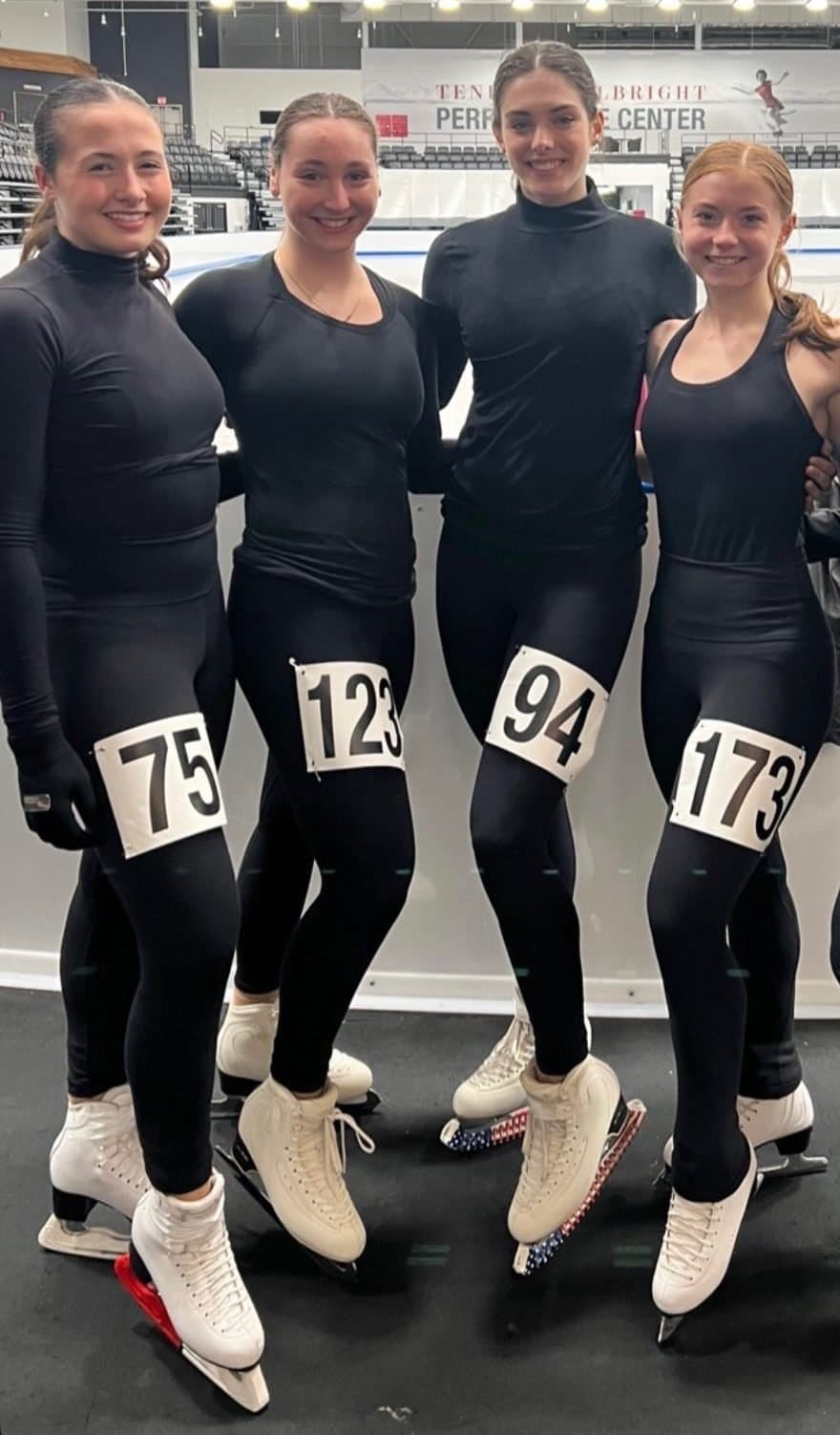Four Hayden skaters in practice gear with competition numbers on their legs, at a placement session