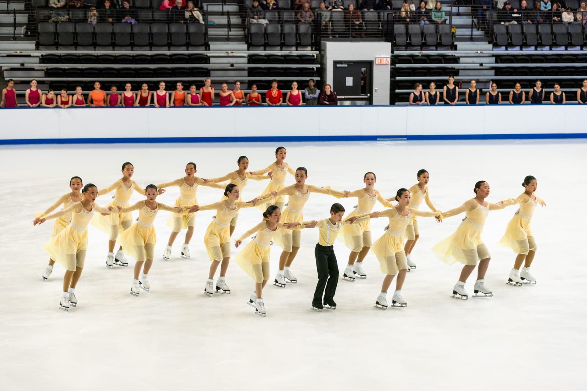 A young Hayden Synchro team in pale yellow dresses skating a connected formation